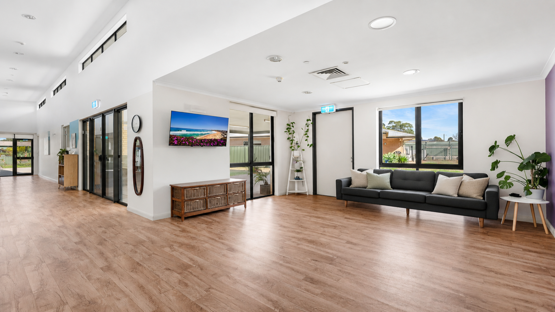 Combined multiple living spaces in the second house with hard wood floors, couches and chairs, seascape artwork, sliding door access to undercover patio.