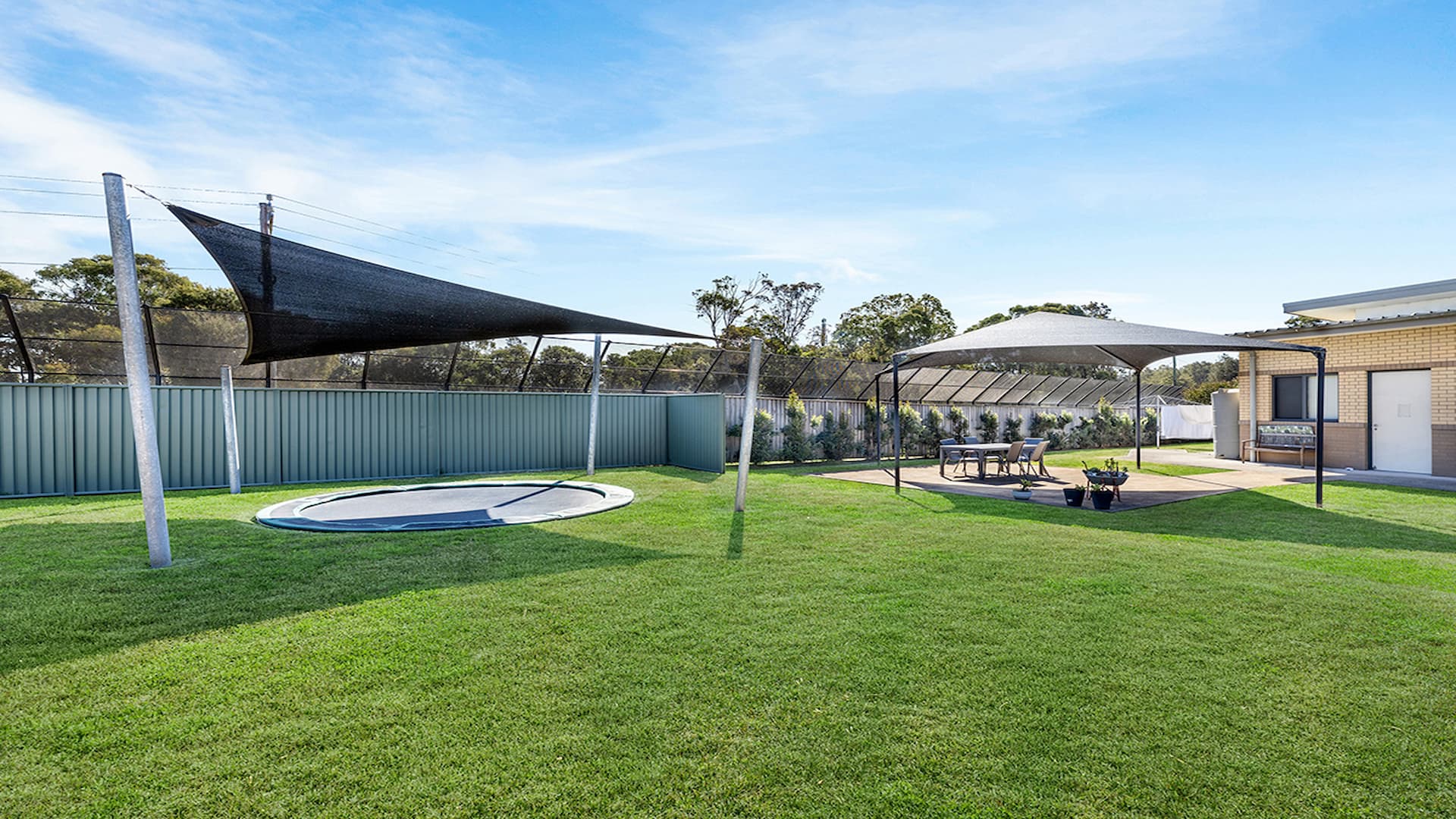 Large lawned space, with undercover inground trampoline and gazebo with table and chairs.